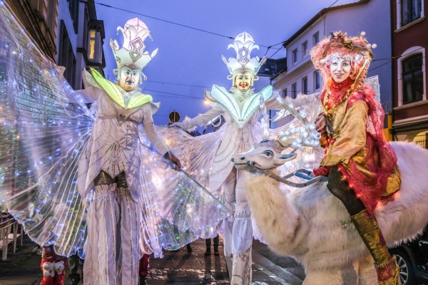 Verkleidete Stelzenläufer mit integrierten Lichterketten laufen durch das Viertel