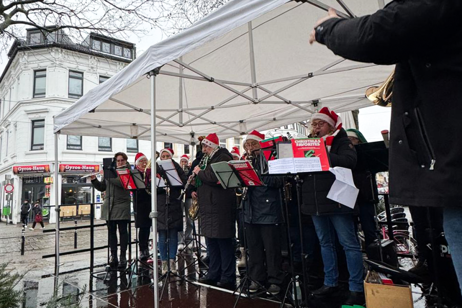 Musiker eines Orchesters spielen auf einer weihnachtlich geschmückten Bühne am Ziegenmarkt
