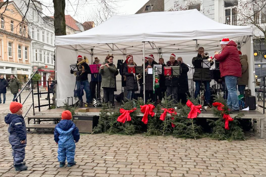 Musiker eines Orchesters spielen auf einer weihnachtlich geschmückten Bühne am Ulrichsplatz